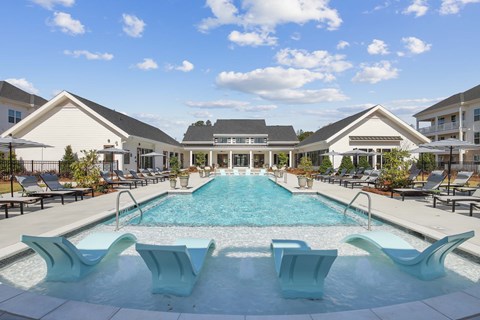 a swimming pool with chairs and a house in the background