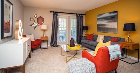 A living room with a red chair and a grey ottoman.