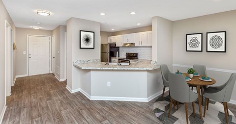 A kitchen with a table and chairs in front of it.