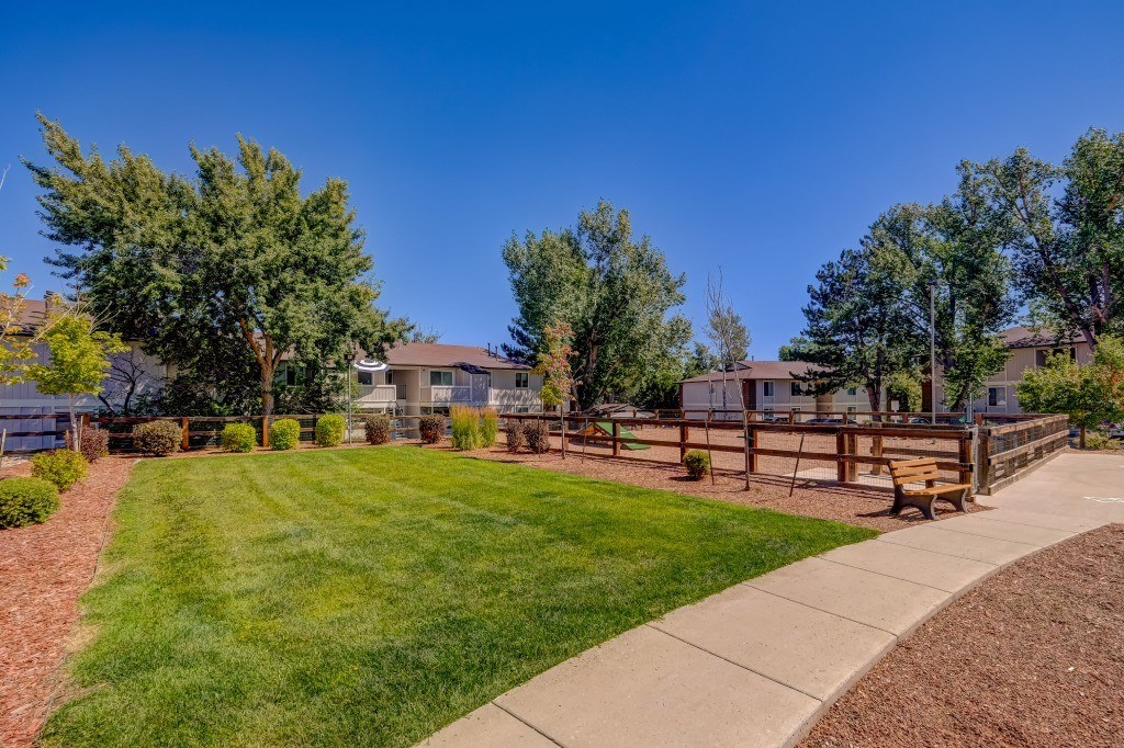 a park with a wooden fence and benches in front of houses