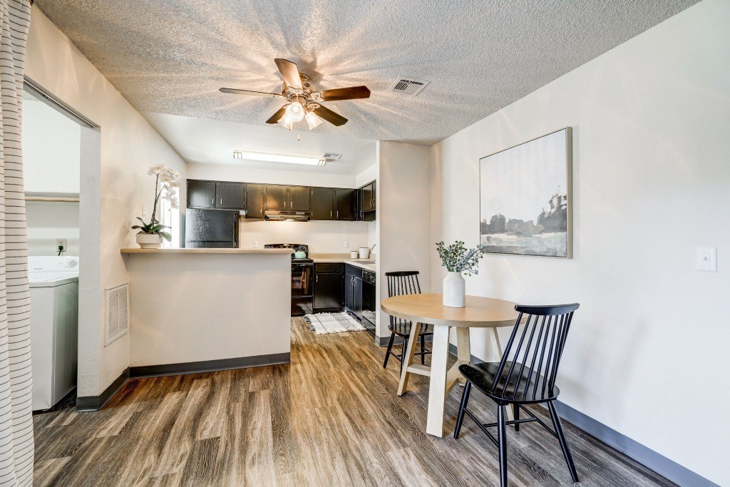 a living room and kitchen with a table and a ceiling fan