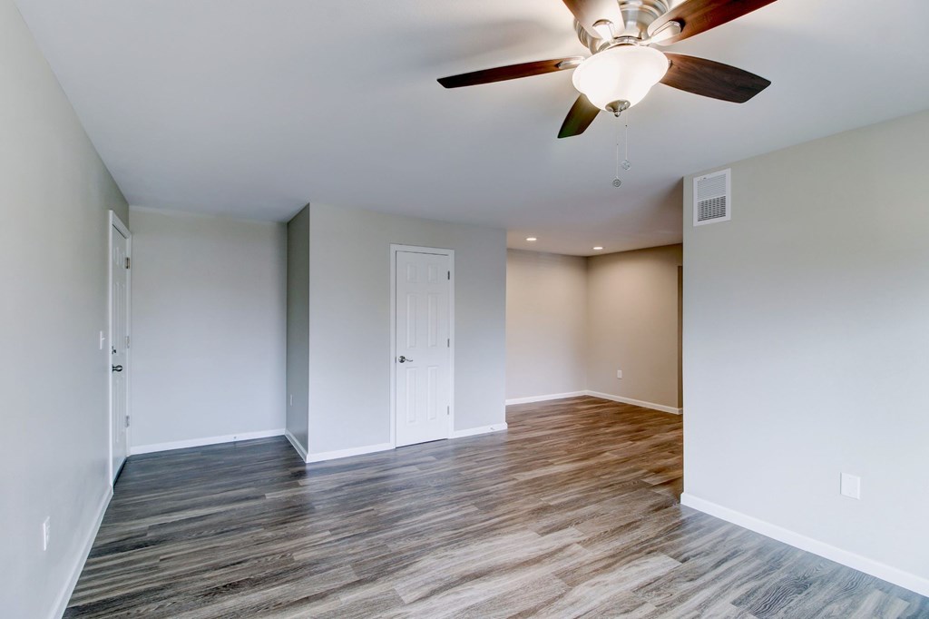 an empty living room with a ceiling fan