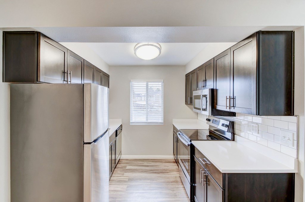 an empty kitchen with stainless steel appliances and wooden cabinets