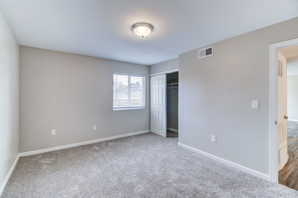 a spacious living room with carpet and a door to a hallway