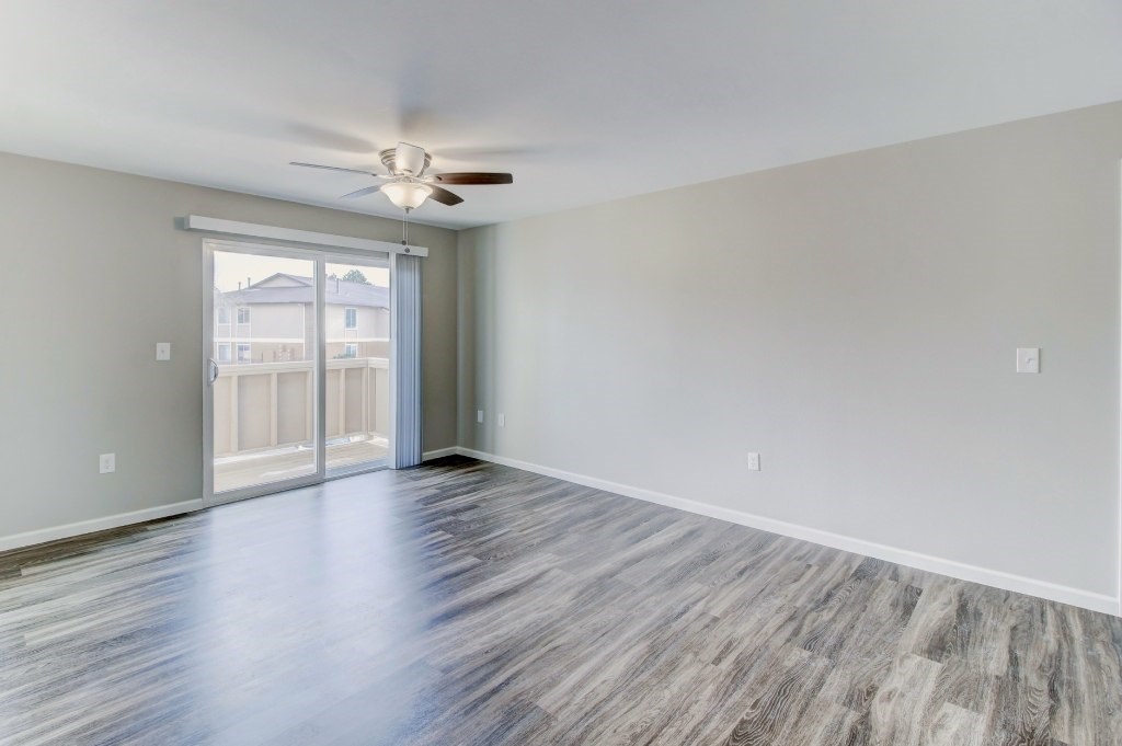 an empty living room with a ceiling fan and a window