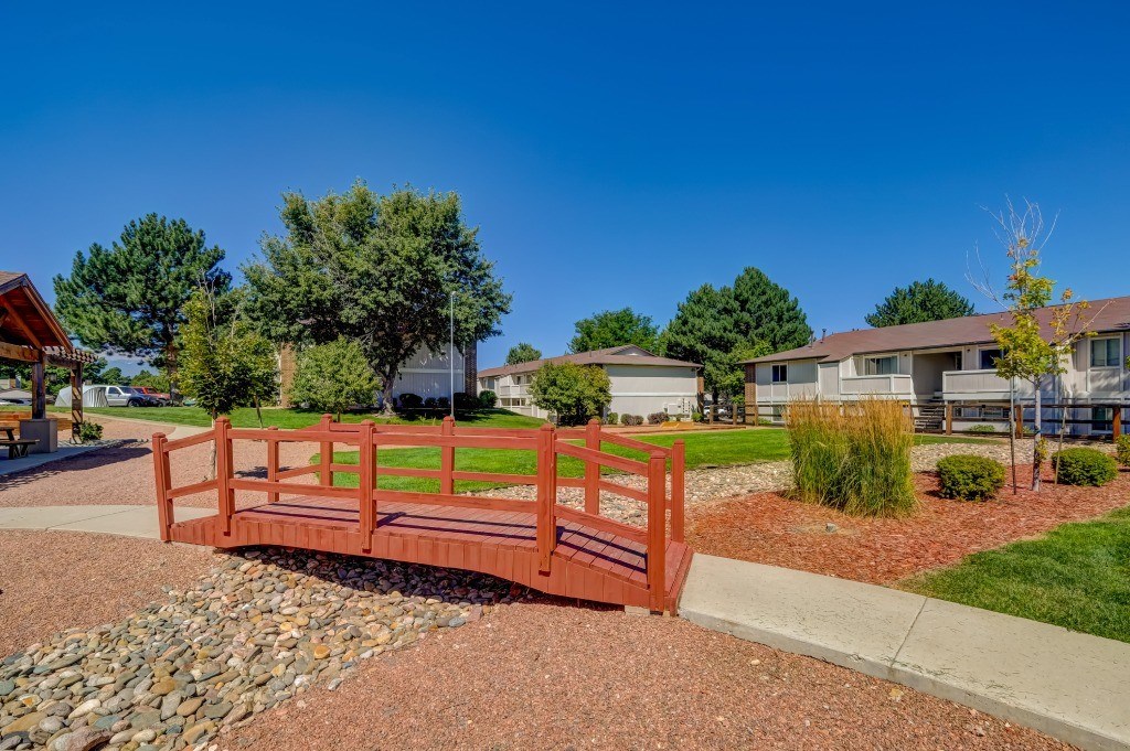 a wooden bridge in a park with houses in the background