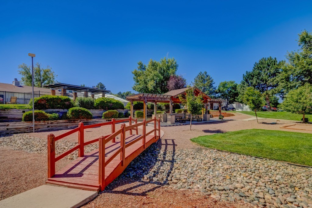 a red bridge over a gravel path leading to a park