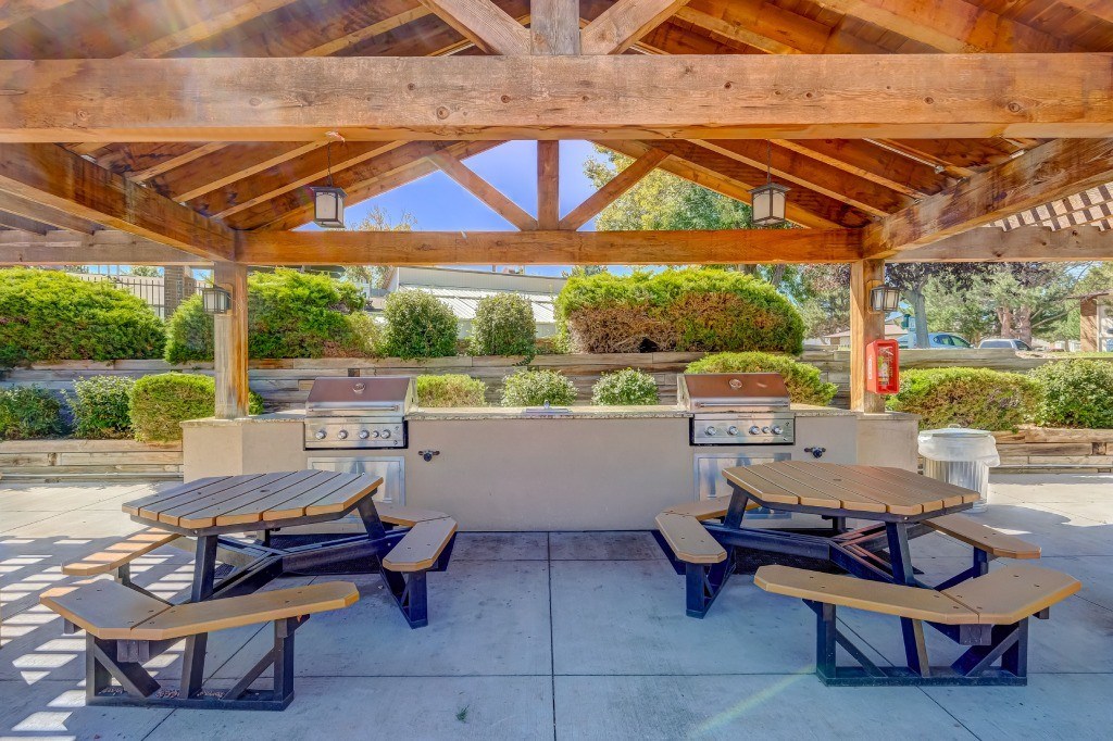 a patio with picnic tables and a barbecue grill