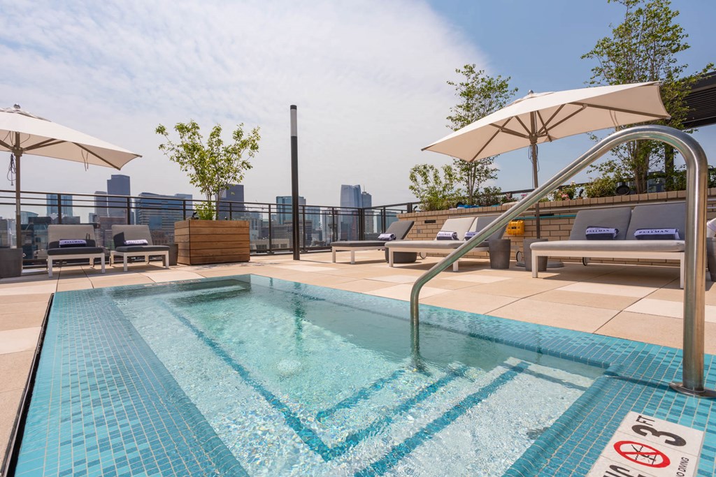 a swimming pool on the roof of a building with chairs and umbrellas