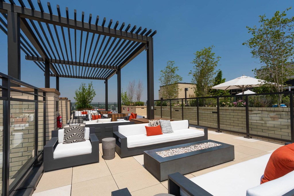a rooftop patio with couches and a pergola
