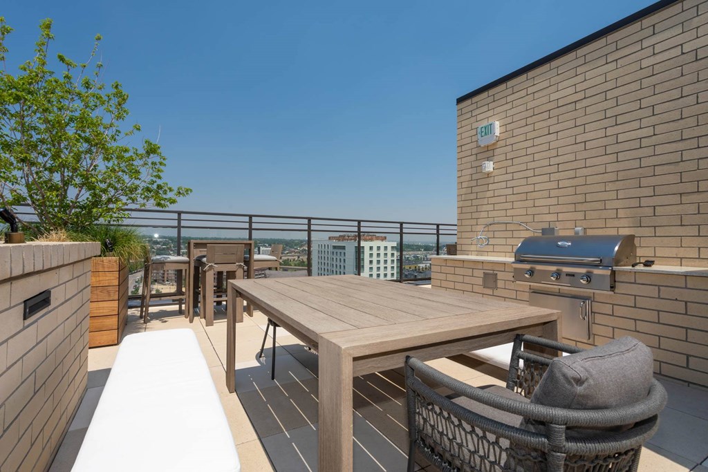 a patio with a table and a grill on a roof
