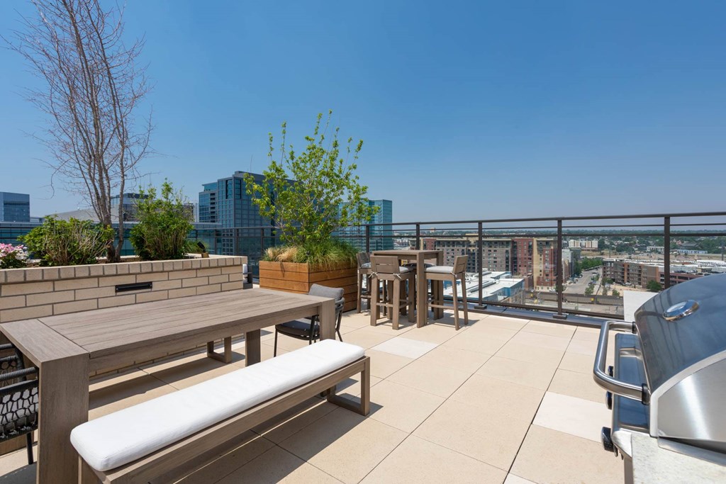 a roof deck with picnic tables and benches and a city view