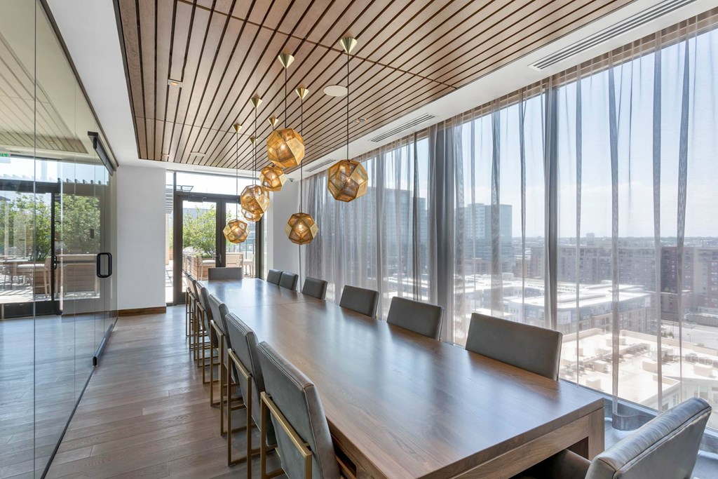 a dining room with a long wooden table and chairs and large glass windows