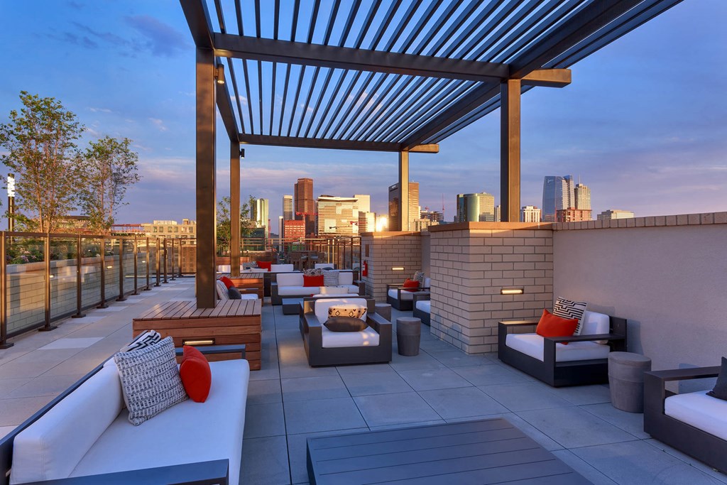 a rooftop patio with lounge furniture and a city skyline in the background
