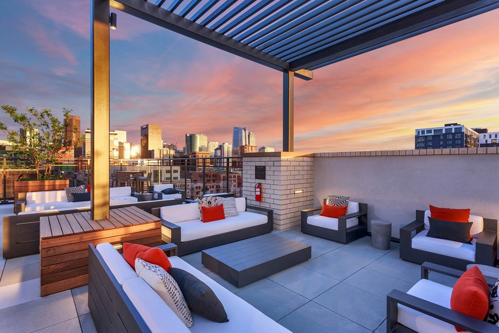 a rooftop terrace with couches and a city skyline at sunset