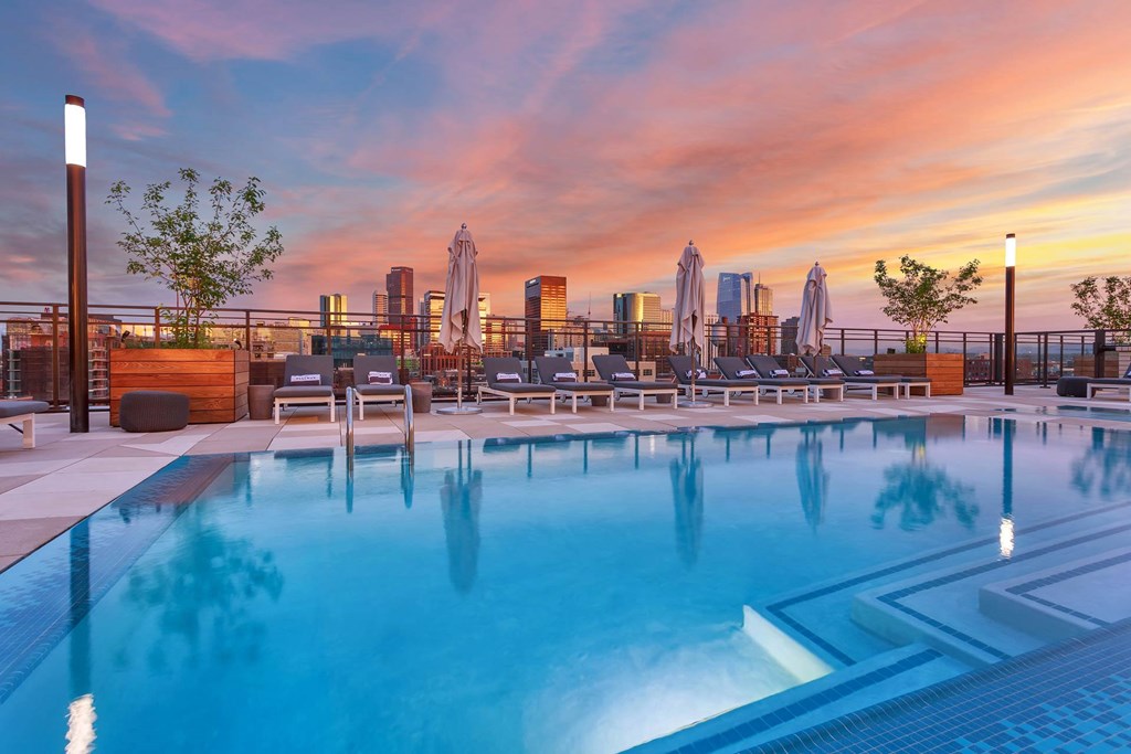 the pool at the envoy hotel at sunset with the city skyline in the background