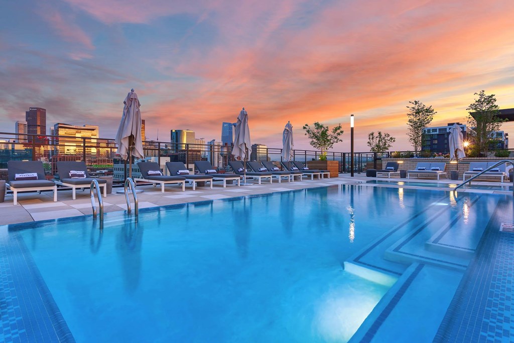 a swimming pool at sunset with the city skyline in the background