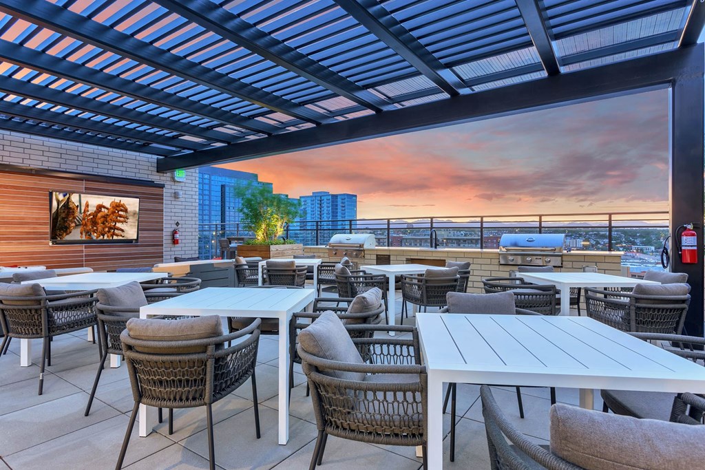 a rooftop patio with tables and chairs and a sunset