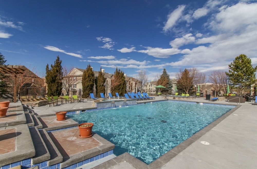 a swimming pool with blue lounge chairs and a blue sky