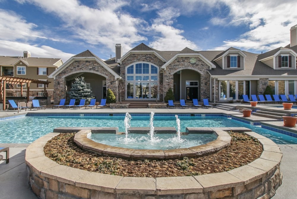 a swimming pool with a fountain in front of a house