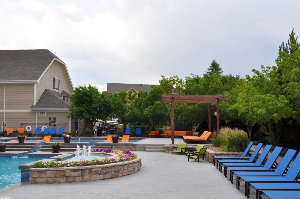 a swimming pool with blue lounge chairs and a fountain