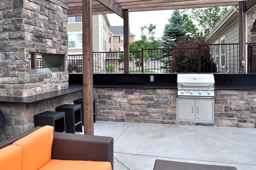 a stone patio with a grill and a bar