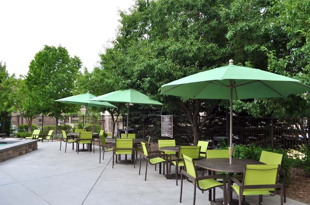 a patio with tables and chairs and green umbrellas