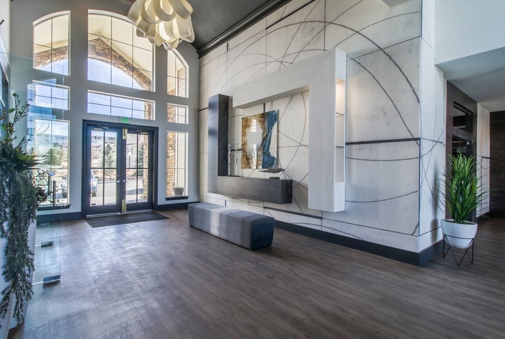 the lobby of a condo with a large glass door and a marble wall