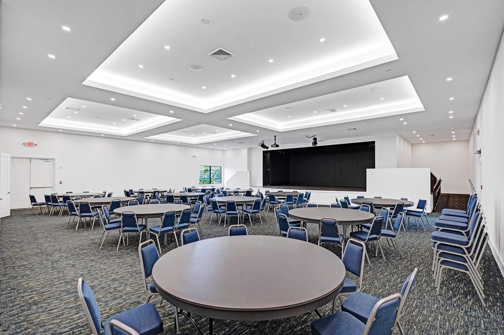 a conference room with tables and chairs and a projection screen