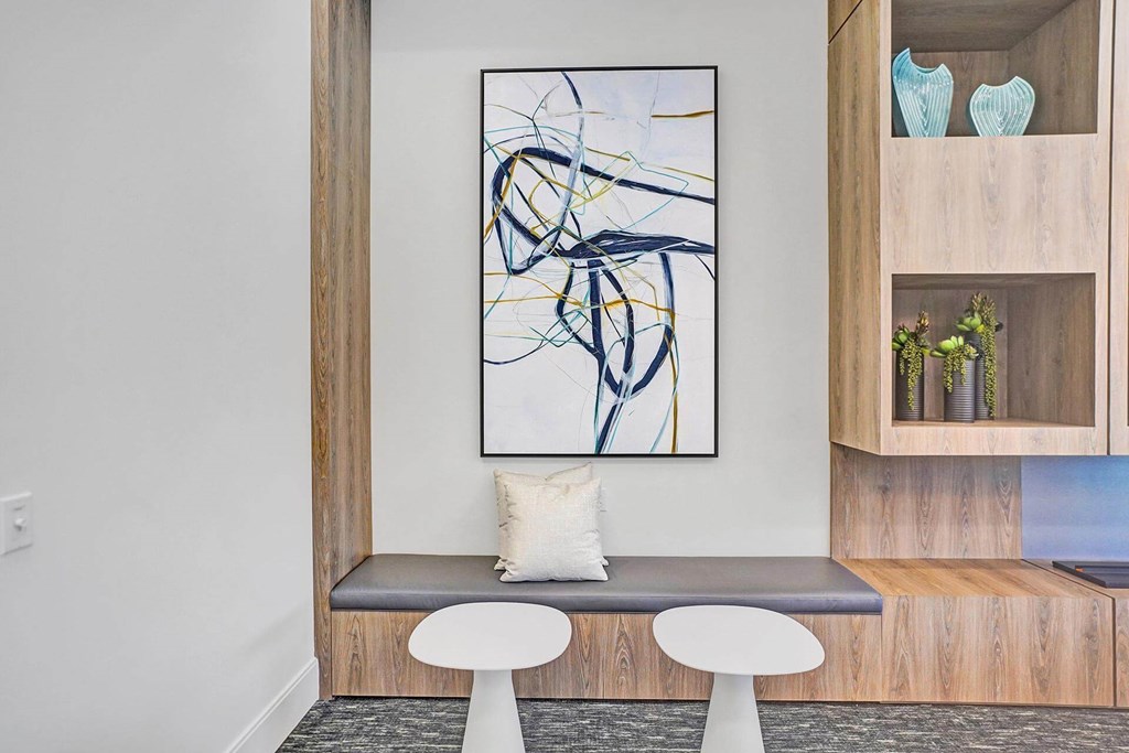 a seating area with two white stools and a painting on the wall