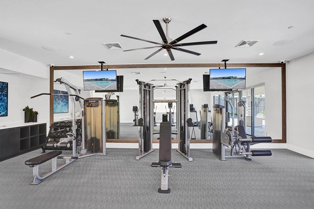 a gym with cardio equipment and a ceiling fan