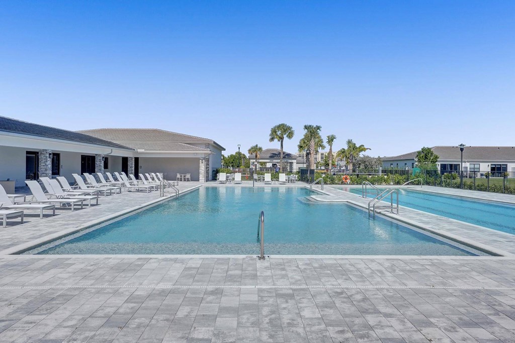 a swimming pool with chairs around it in front of a building