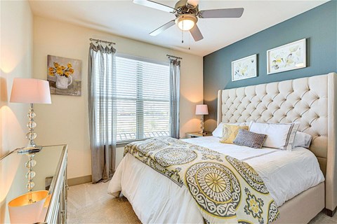 A bedroom with a large bed and a ceiling fan.