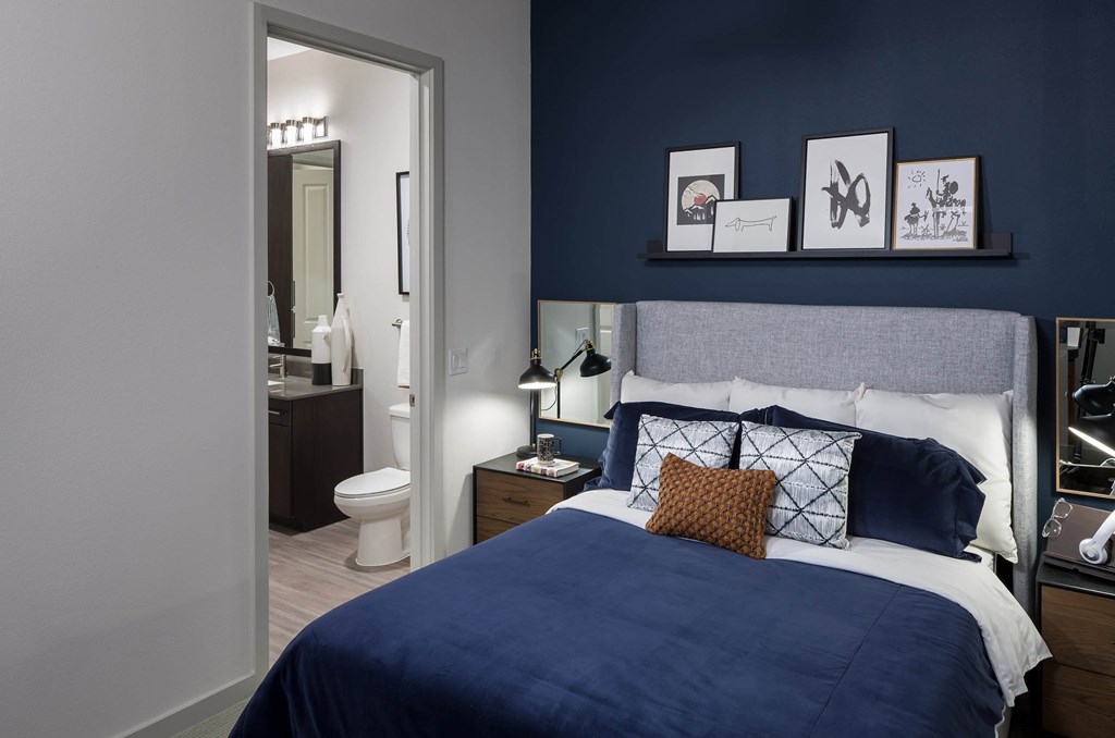 a bedroom with a bed and a blue wall and a bathroom