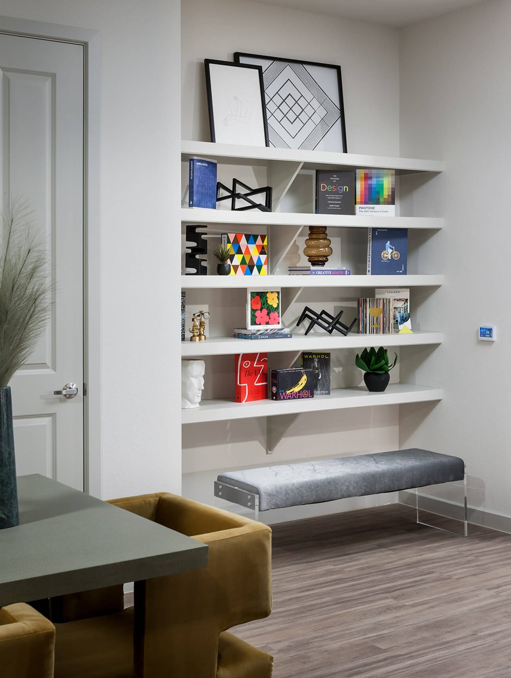 a living room with a shelf and a table and chairs