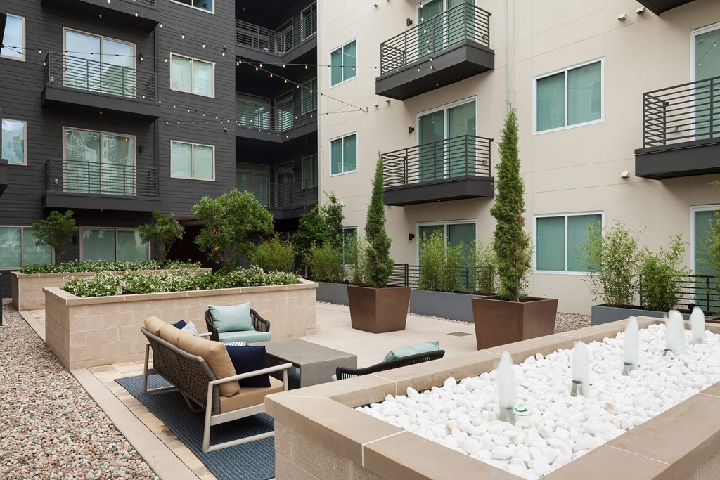an outdoor seating area with chairs and tables in front of an apartment building