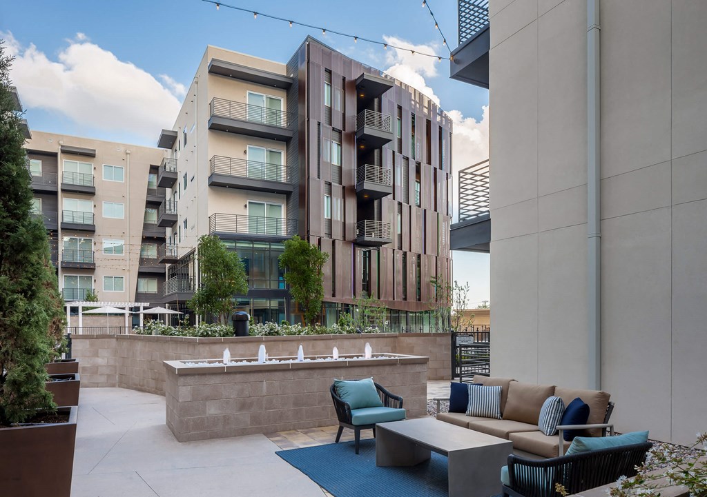 a patio with couches and chairs in front of an apartment building