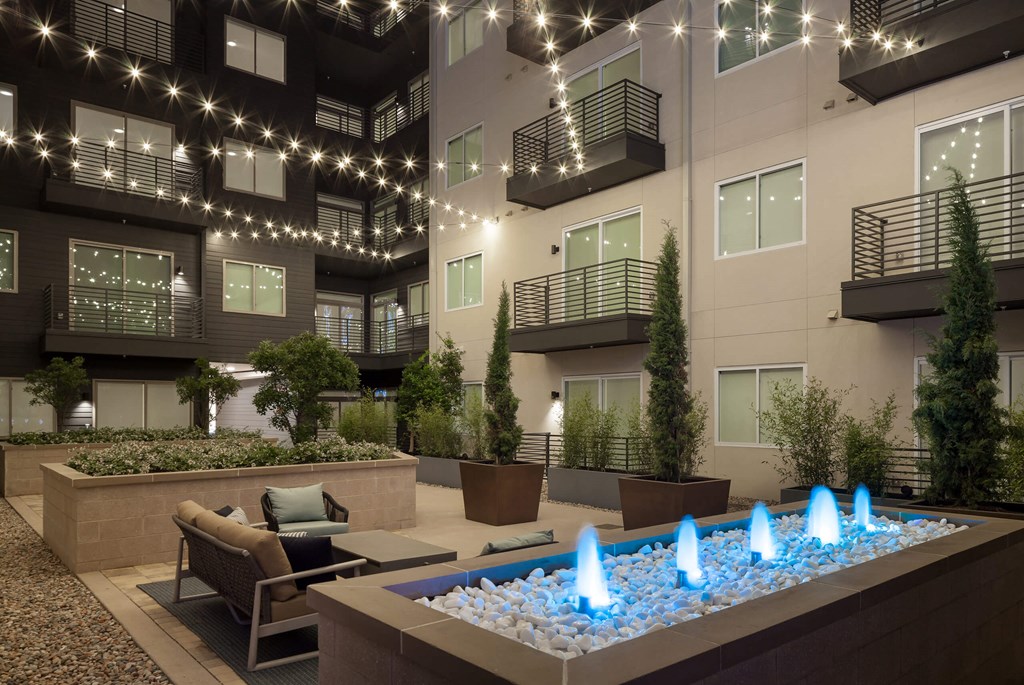 a fountain in front of an apartment building with lights