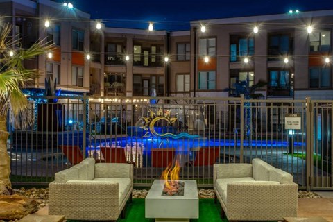 A pool with a fire pit in front of a building at night.