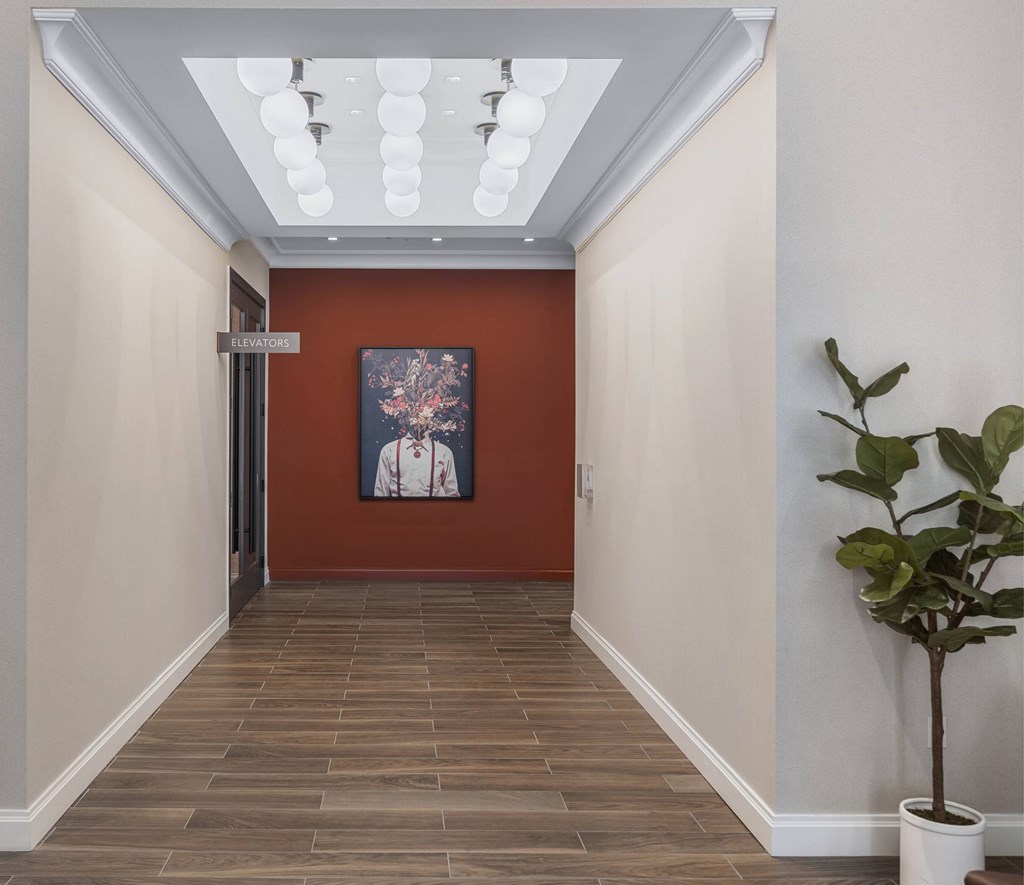 a hallway with a plant and a painting on the wall