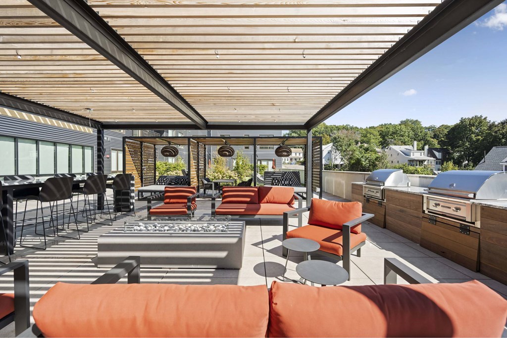 a patio with orange chairs and tables and a grill