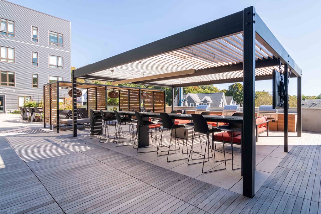 a rooftop patio with tables and chairs and a pergola