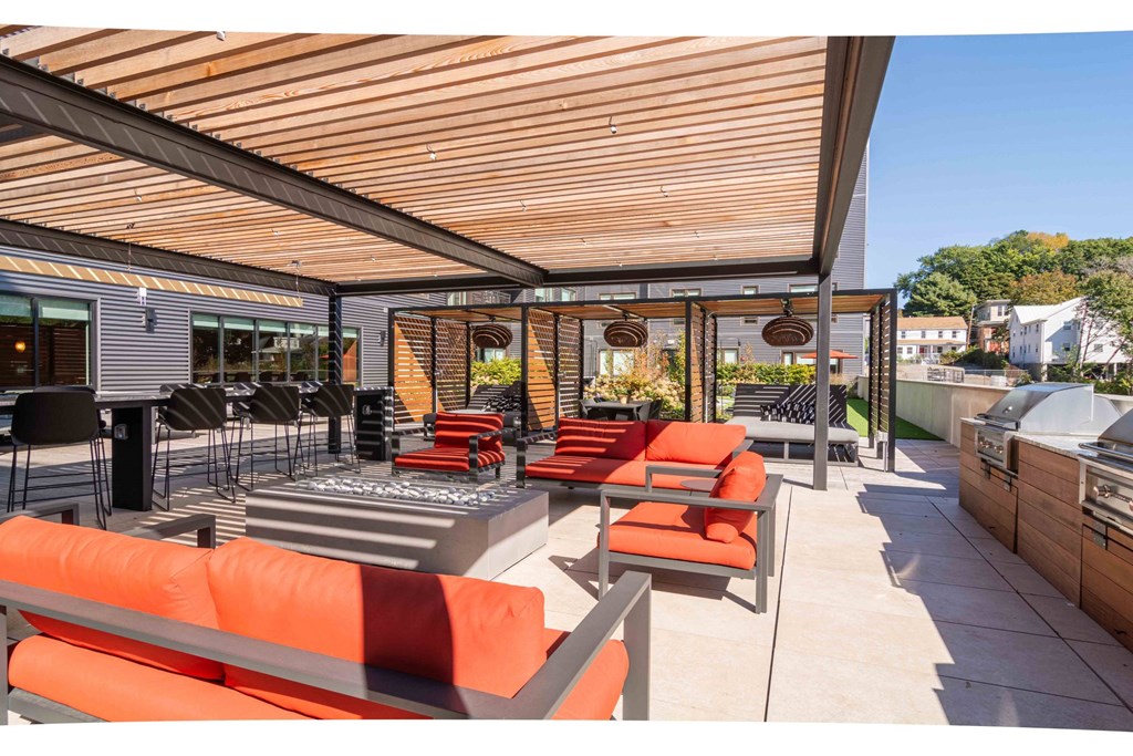 a patio with orange chairs and tables and a wooden roof