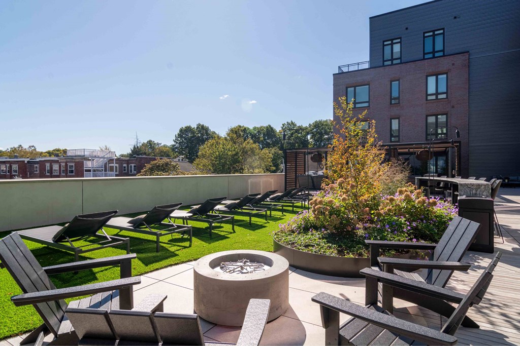 a rooftop patio with lounge chairs and a fire pit