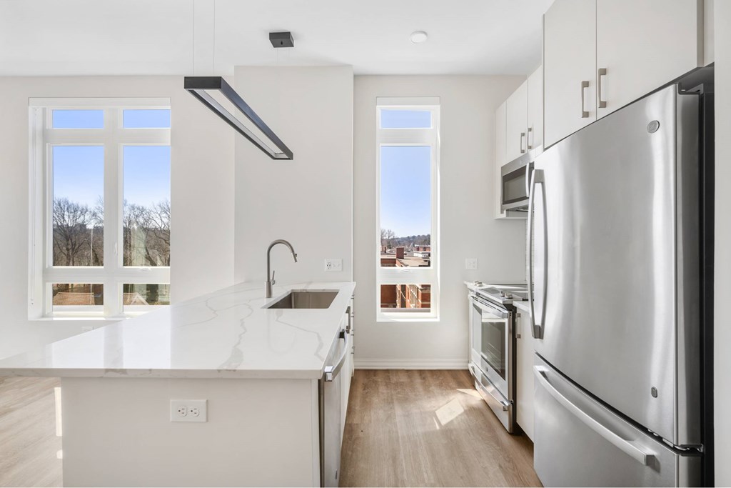 a white kitchen with stainless steel appliances and a large window