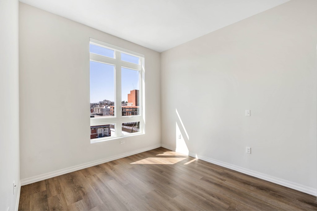 a living room with a large window and hardwood floors