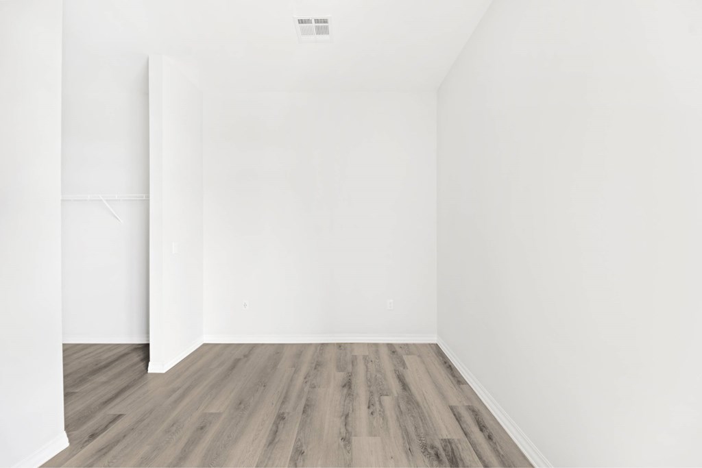 an empty room with white walls and wood floors