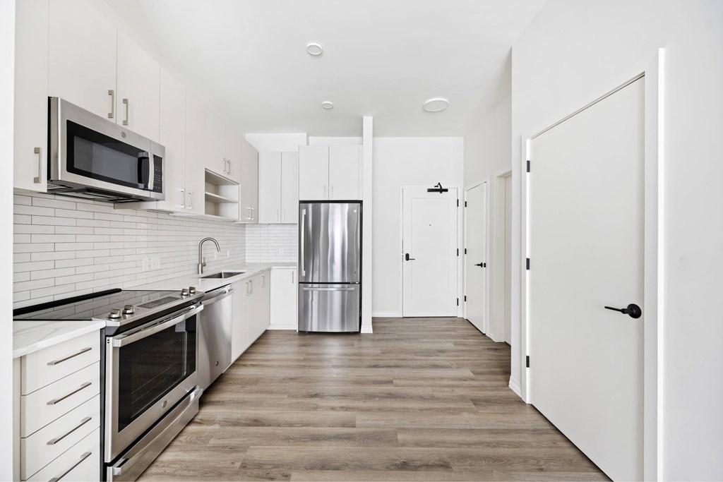 a white kitchen with stainless steel appliances and white cabinets