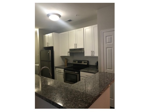 a kitchen with white cabinets and a granite counter top