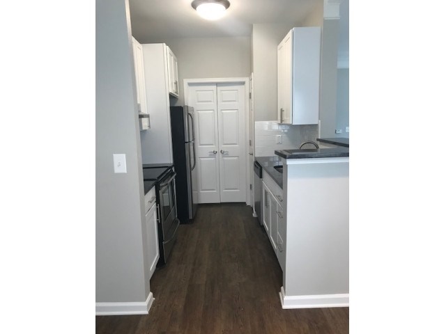 a kitchen with white cabinets and a black refrigerator
